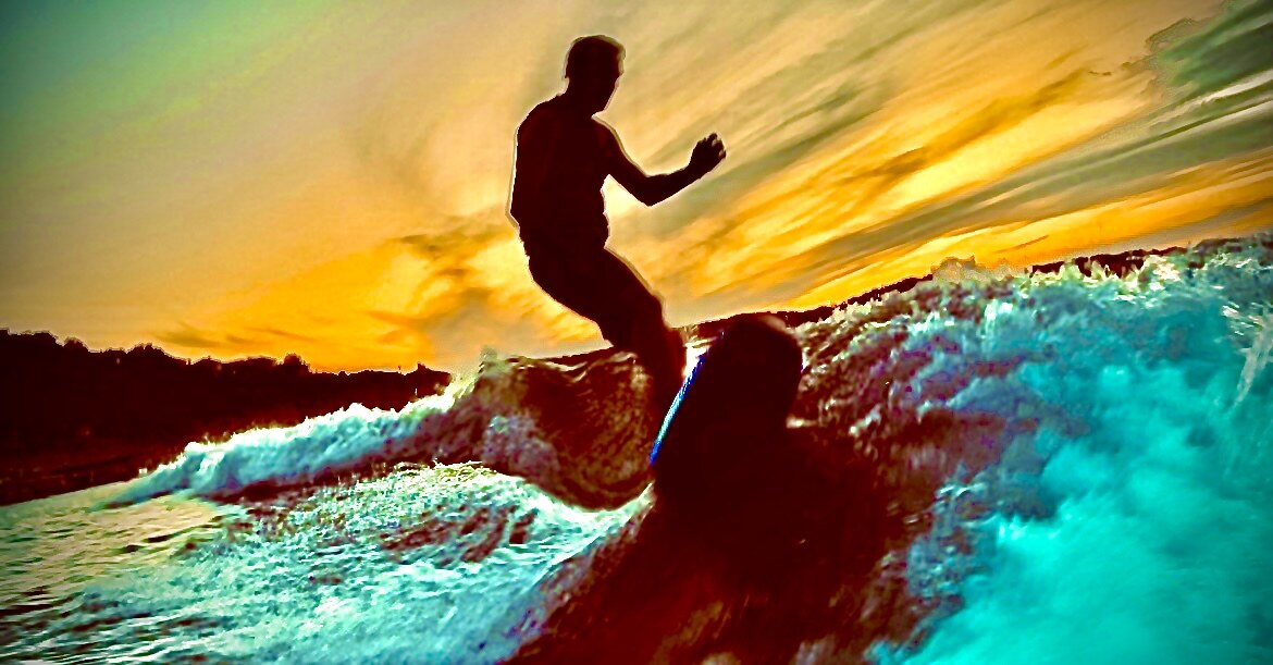 A wakesurfer silhouetted against a vivid Lake Travis sunset